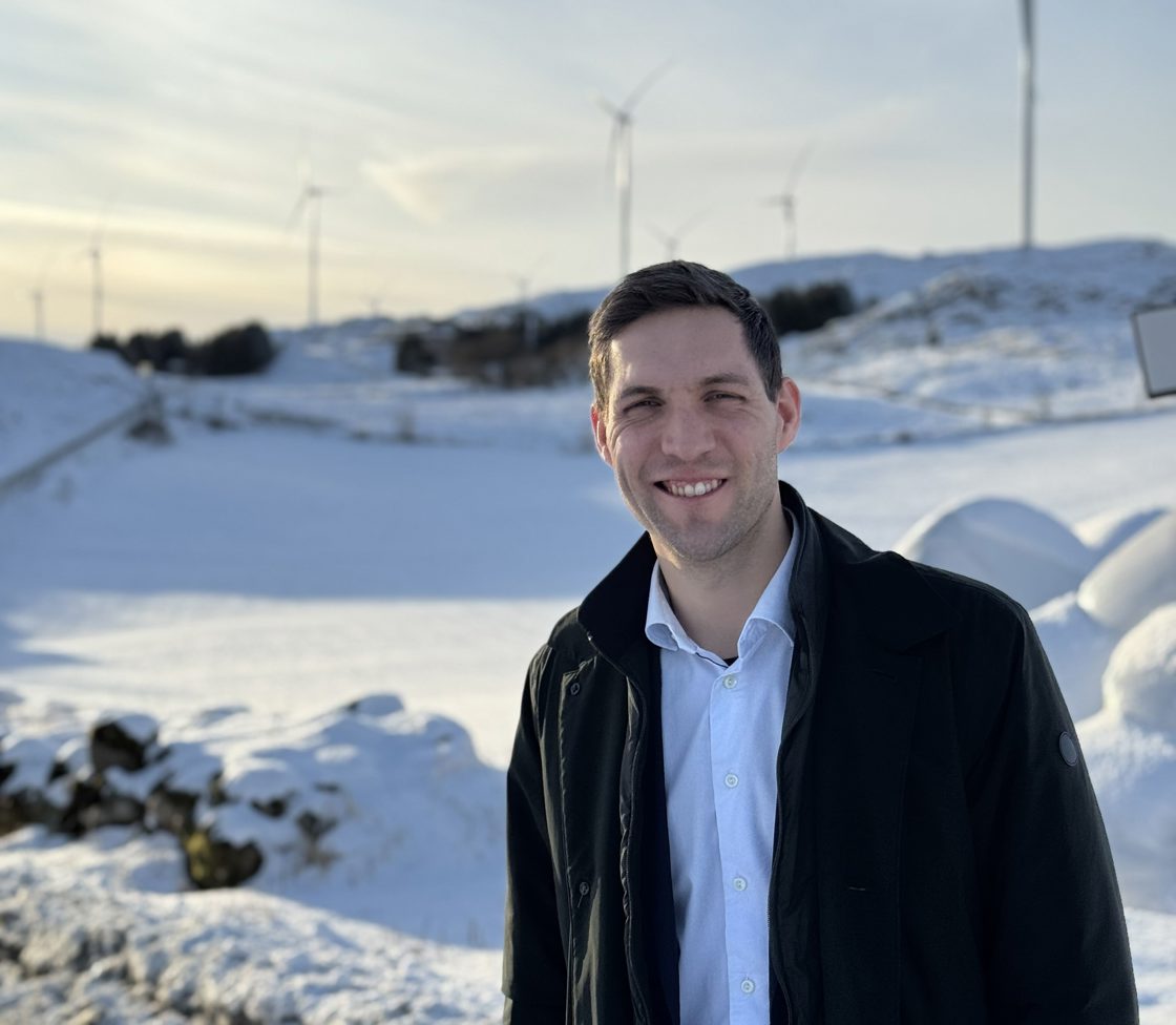 Klima- og miljøminister Andreas Bjelland Eriksen ved Høgjæren vindpark, foran vindturbiner.