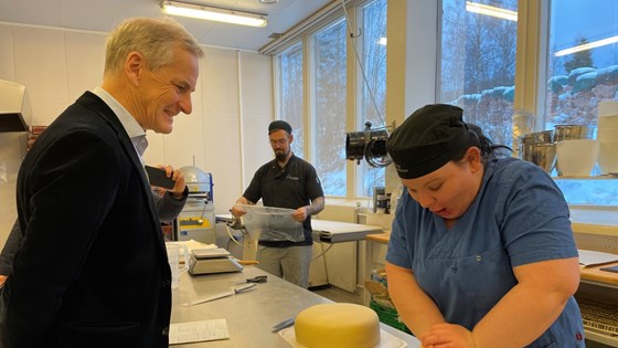Statsministeren ser på en medarbeider som baker marsipankake.