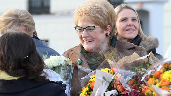 Nyutnevnt kulturminister Trine Skei Grande på slottsplassen med armene fulle av blomsterbuketter.