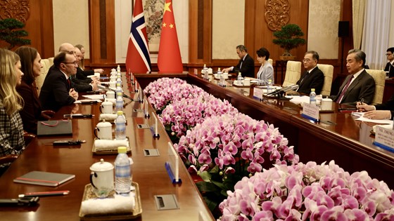 Bilde av den norske delegasjonen og den kinesiske motparten sittende på hver sin side av bordet med blomster i midten