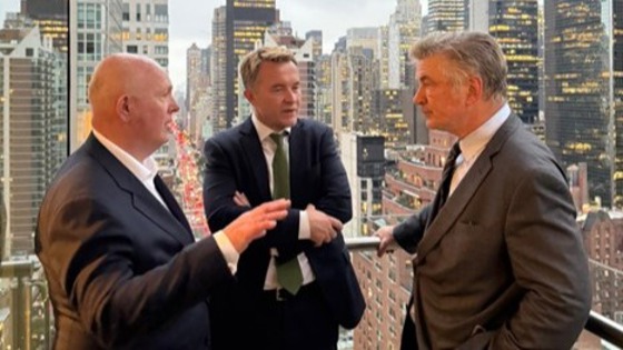 Tre menn i dress med skyskraper i bakgrunnen