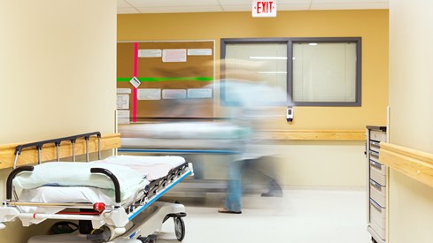 Bilde av en sykehuskorridor med en utydelig mann i bevegelse