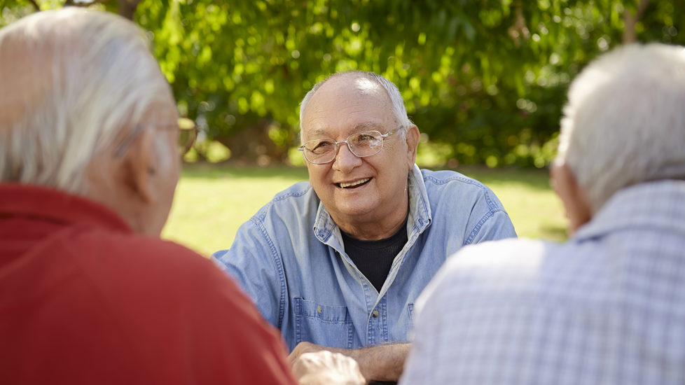 Tre eldre menn i samtale på en sommerdag