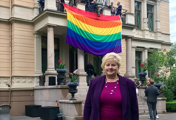 Erna Solberg foran regnbueflagget.