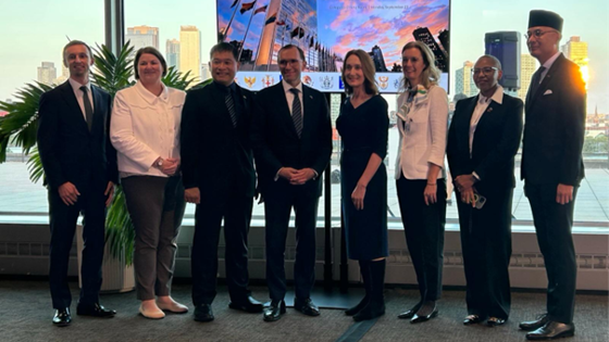 Menn og kvinner fremfor et vindu med skyskraper i bakgrunnen