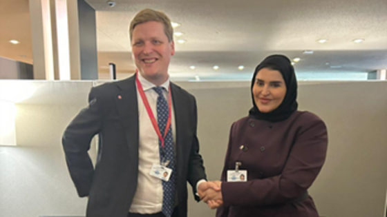 En mann i dress og en kvinne som hilser på hverandre