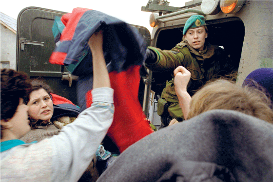 Figur 4.6 En soldat fra TMBN deler ut klær til kosovoalbanske familier i en landsby i Kosovo. 
