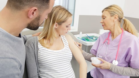 Helsepersonell setter vaksine på en gravid kvinnes overarm