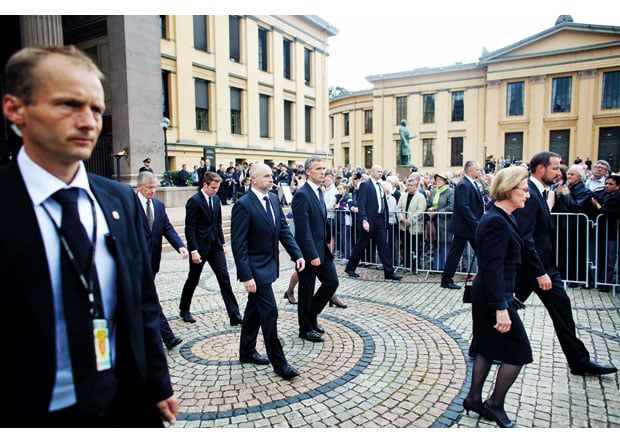 Figur 10.12 Medlemmer av kongefamilien, AUFs leder, og representanter fra det offisielle Norge omgitt av livvakter etter å ha signert kondolanseprotokollen i Universitetets aula 25. juli.