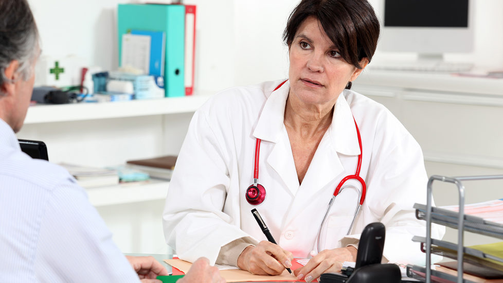Kvinnelig fastlege i samtale med pasient på legekontor