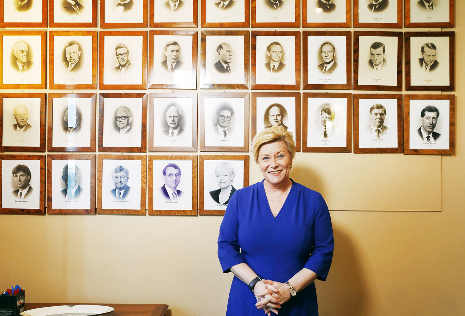 Finansminister Siv Jensen står foran bilde av tidligere statsråder