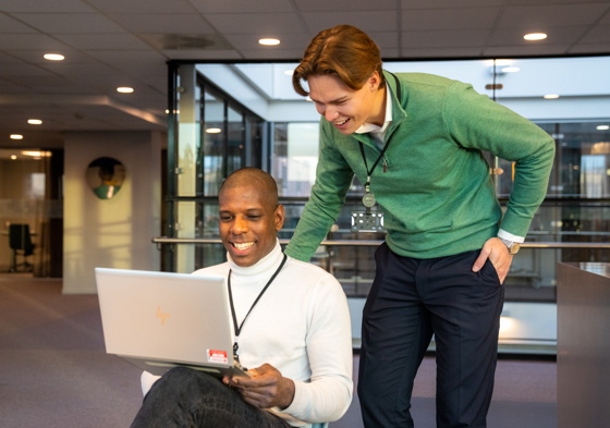 To kolleager som diskuterer noe over datamaskinen