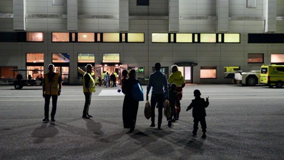 En familie med barn går mot en flyplassbygning