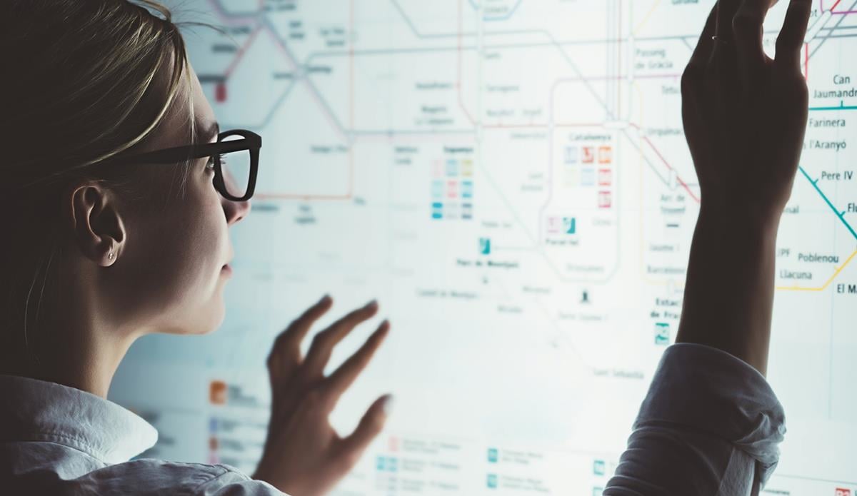 Kvinne ved en stor berøringsskjerm med et komplekst diagram.