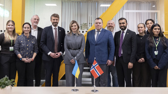 Group photo of the delegation during First Lady Zelenska's visit. Several people are in the picture. First Lady Zelenska is in the middle of the photo with Minister of Health and Care Services Jan Christian Vestre to her left. Norwegian and Ukrainian flags are displayed on the table.