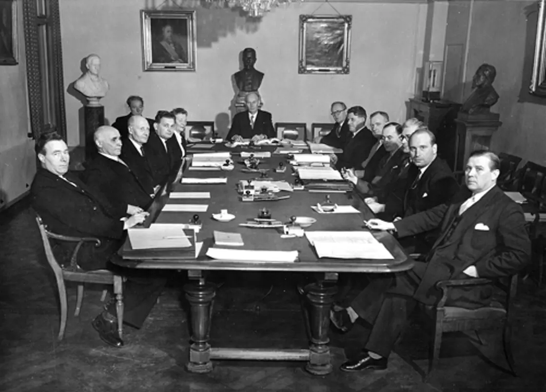 Sort-hvitbilde fra et møterom i Victoria Terrasse i 1948. Regjeringsmedlemmer rundt bordet.