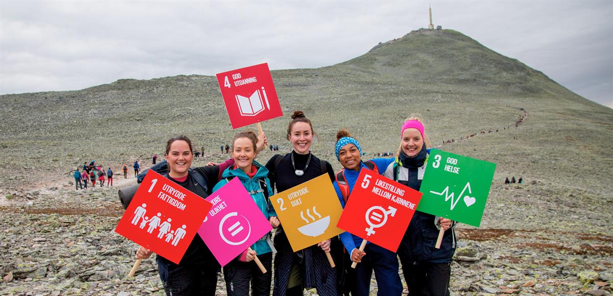 Picture of Norwegian youth with SDG signs on a mountain top.