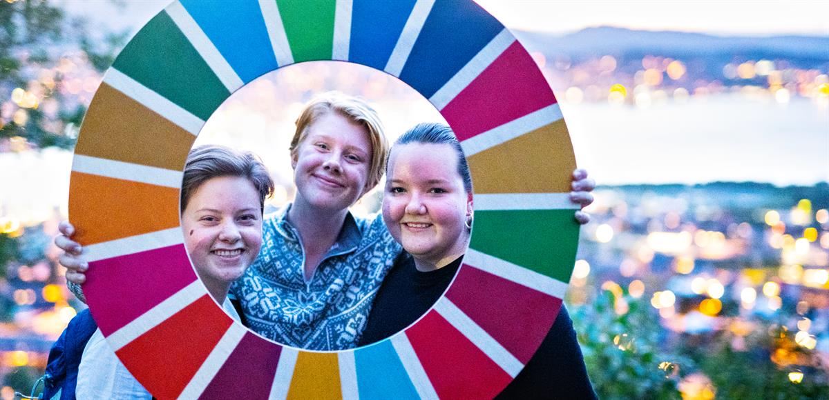 Picture of three children holding a circle with the SDG colors.