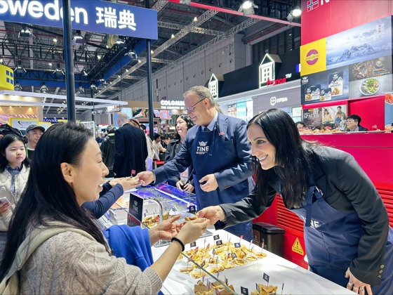 Statssekretær Brekken deler ut brunost på Norges paviljong på den store messen CIIE, i Shanghai.