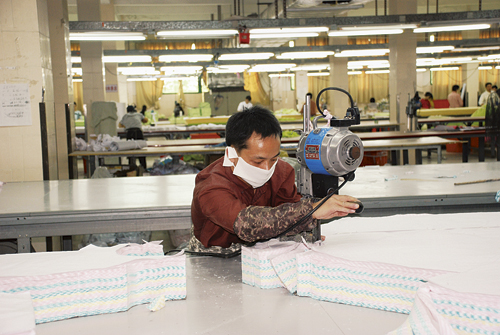Figur 3.6 Tekstilproduksjon i Kina. Bruk av munnbind eller støvmasker
 er et enkelt og nødvendig verne­tiltak for tekstilarbeidere.