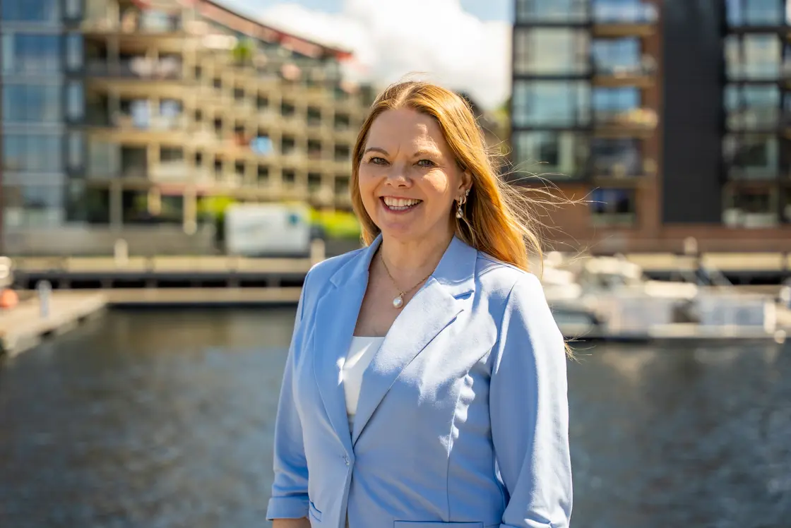 Kvinne står på en brygge med bygninger i bakgrunnen