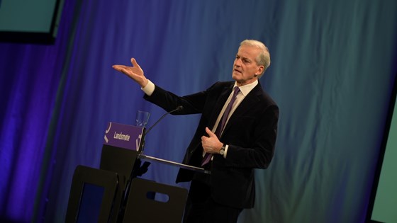 Statsminister Jonas Gahr Støre gestikulerer på scenen.