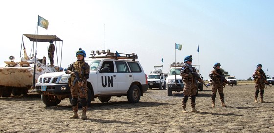 Uniformert FN-personell står oppstilt foran FN-biler