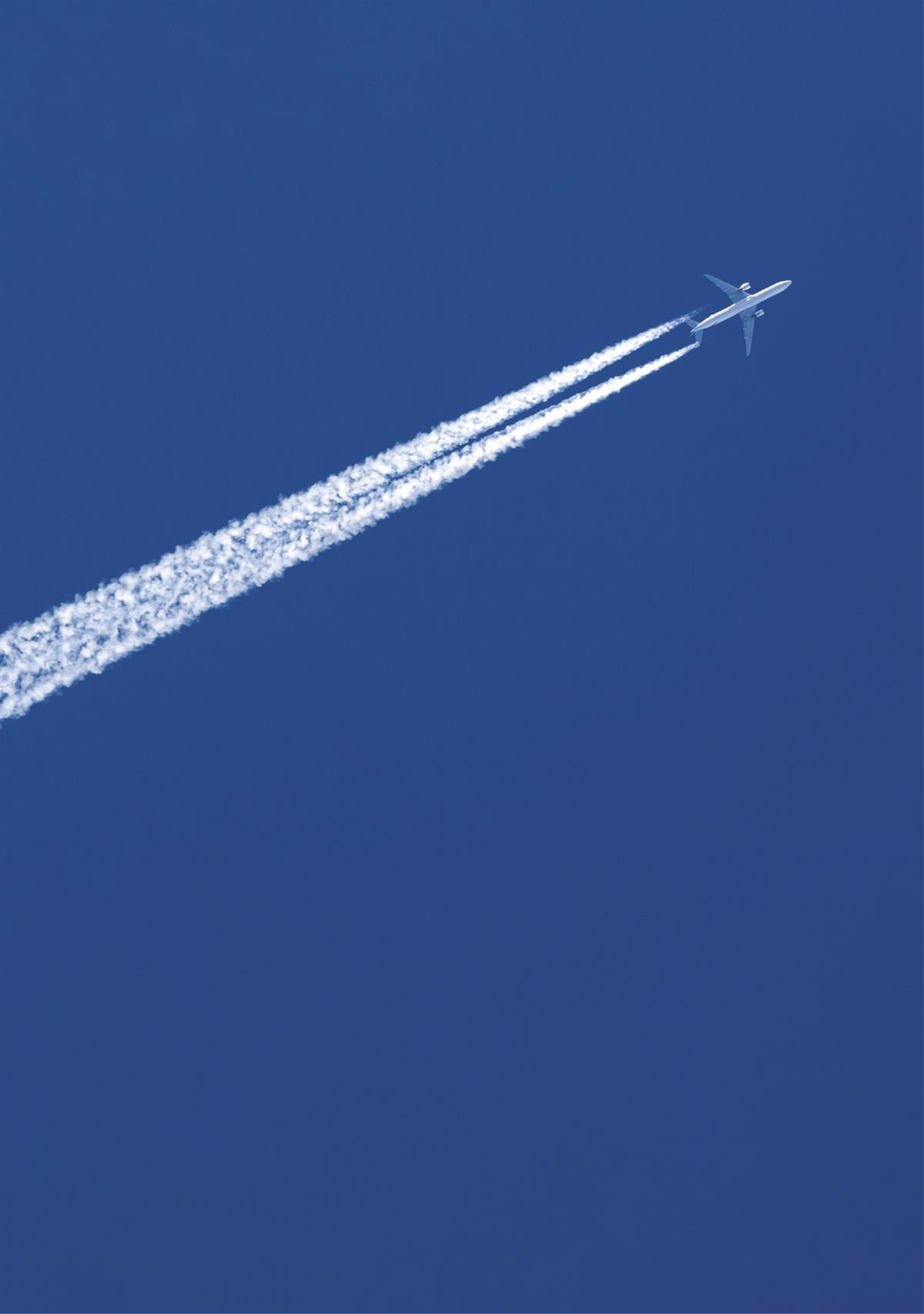 Foto av fly som flyr over himmelen med kondensstriper bak