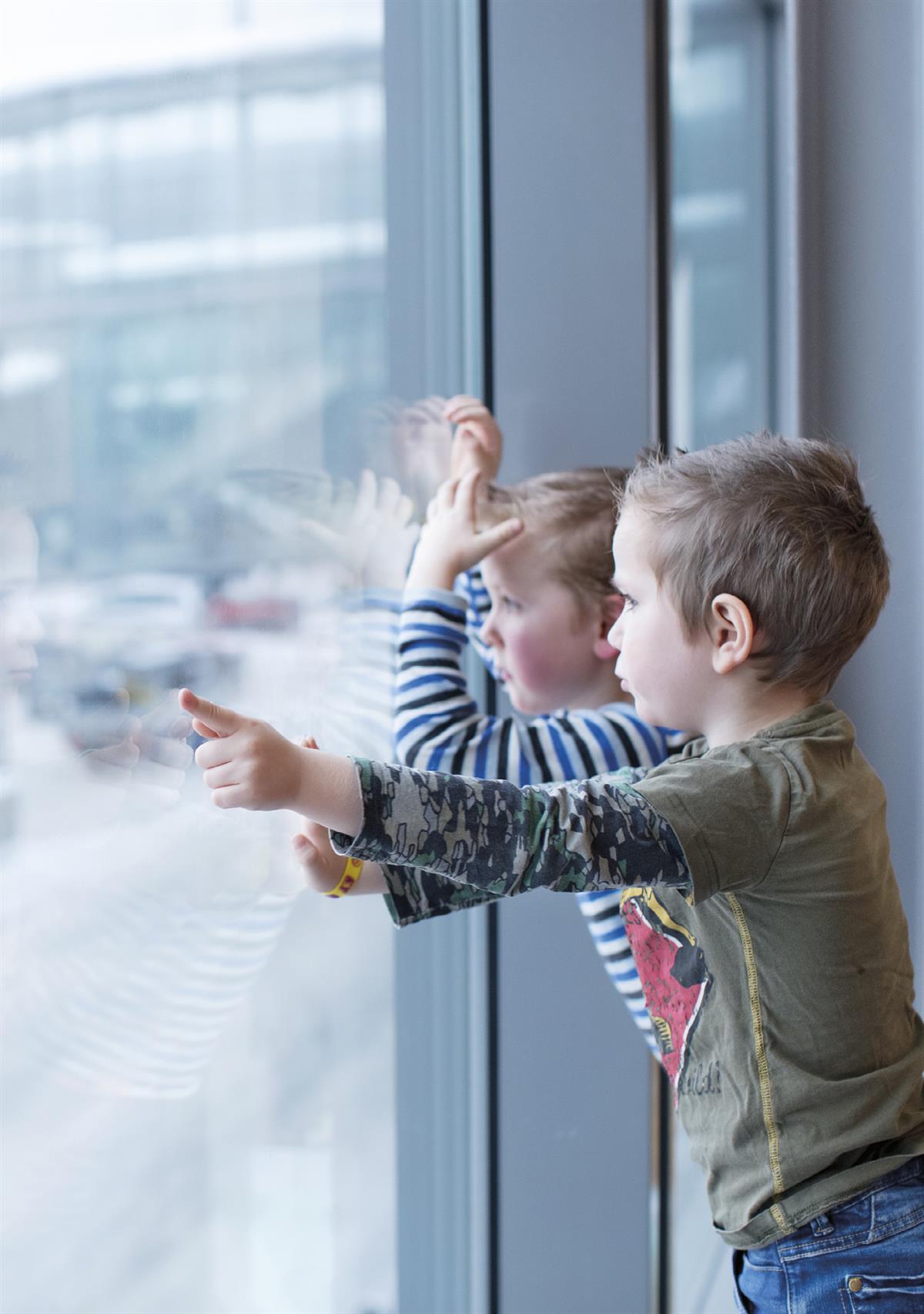 To barn som ser ut gjennom vinduet på en flyplass