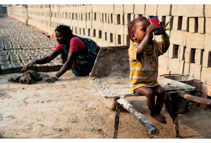 Figur 2.5 India. Et barn leker med ny teknologi, mens moren arbeider. 
