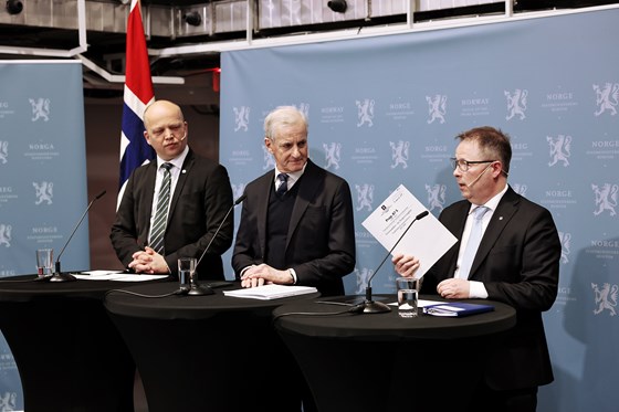 Fra venstre: Finansminister Vedum, statsminister Støre, forsvarsminister Gram. De står foran en blå pressekonferansevegg fra SMK. 