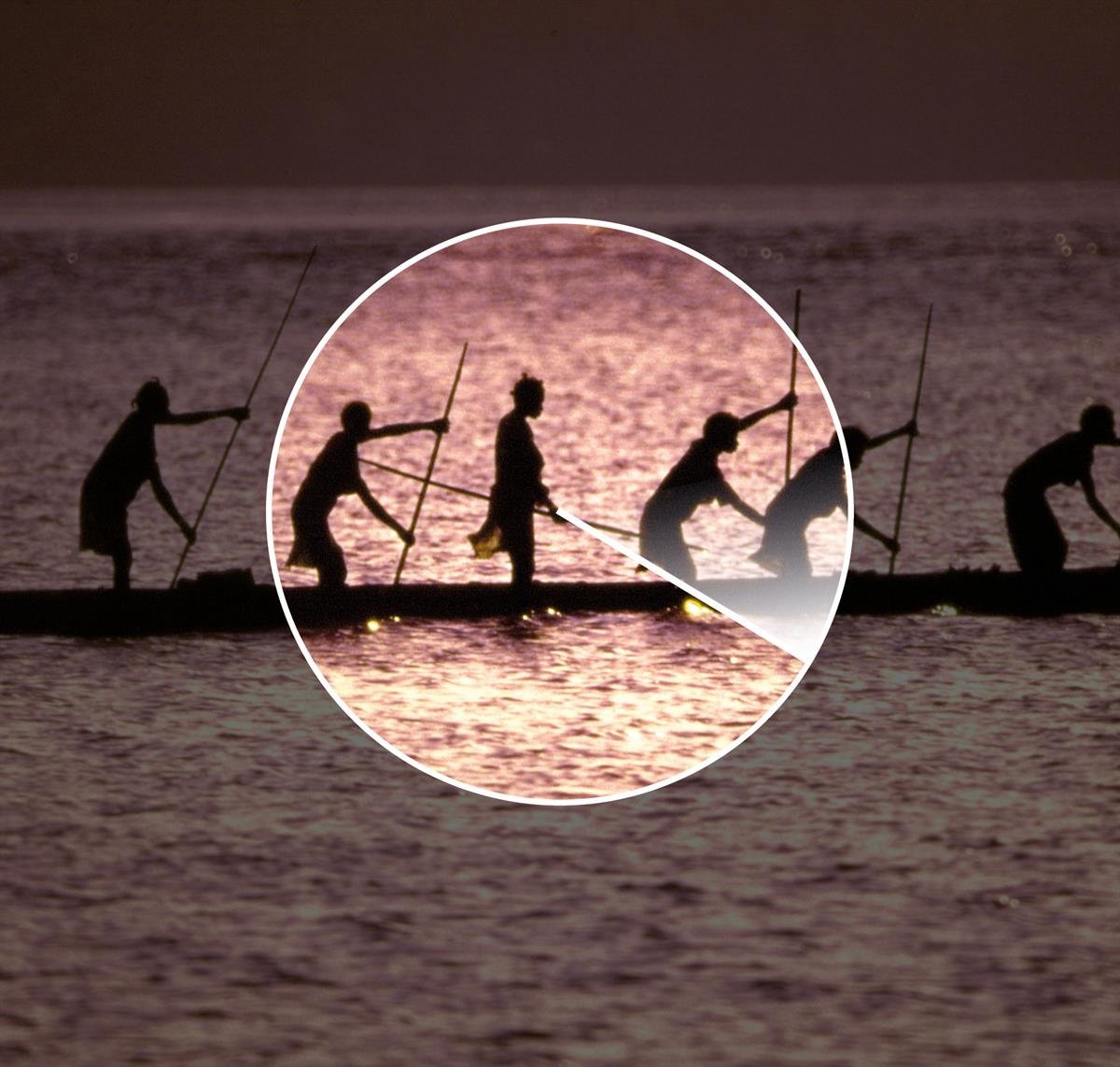 Silhouettes of Indigenous people paddling a long canoe on the water at sunset.