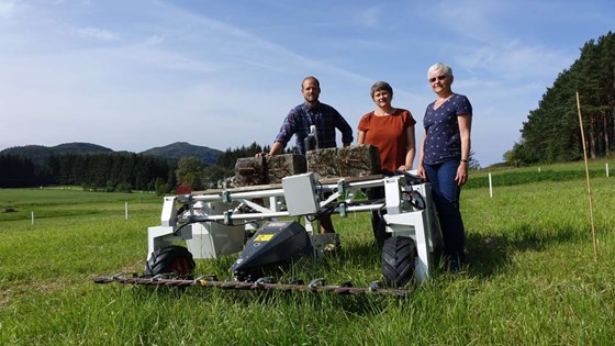 Forskerne Anders Aune, Synnøve Rivedal og Liv Østrem med roboten Thorvald på forsøksfeltet ved NIBIO Fureneset august 2019.