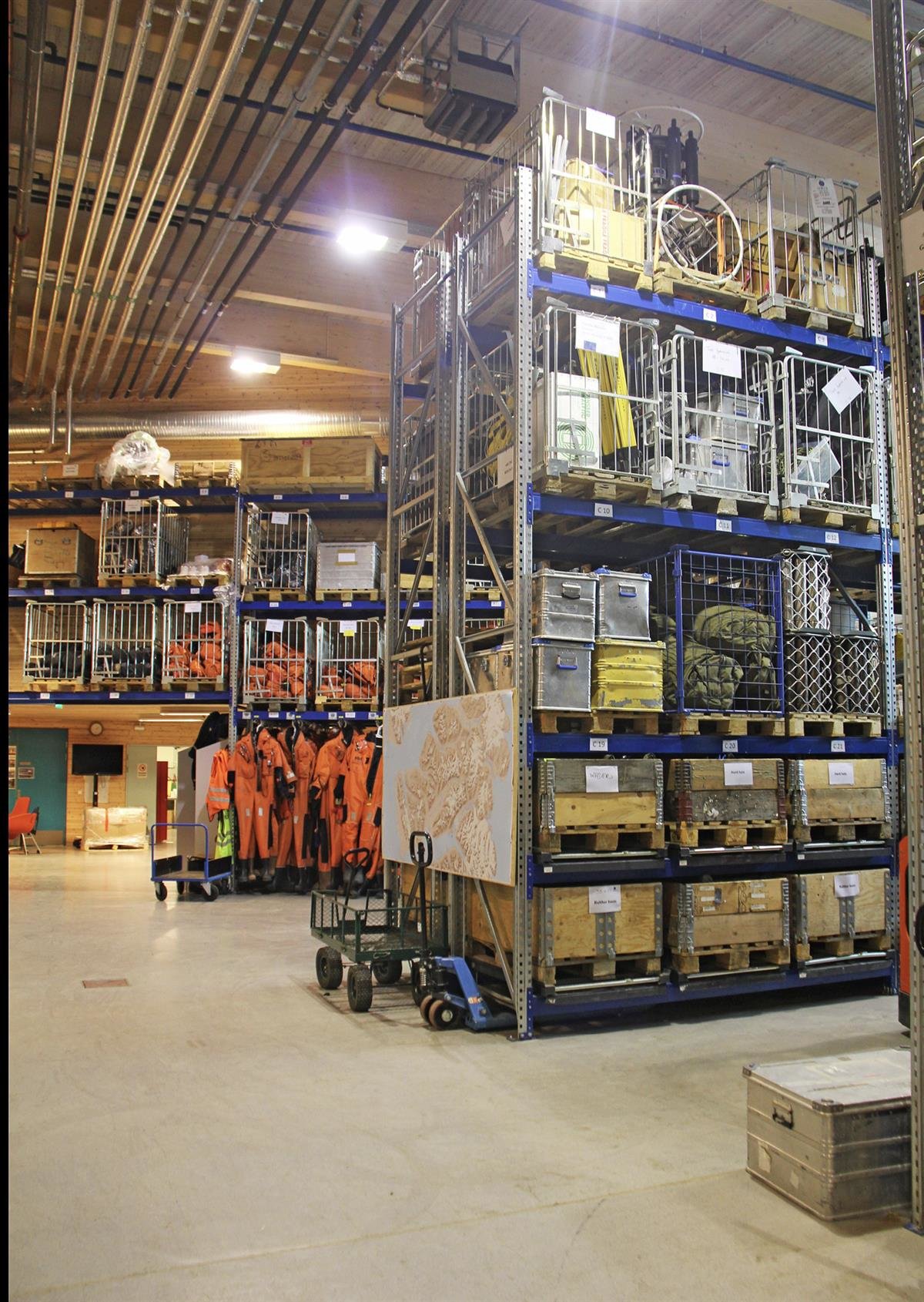 Logistikklageret i Forskningsparken, Longyearbyen. Lagerhall med hyller som strekker seg til taket fylt med feltutstyr i kasser og bur. Foto: Jan Roald / NP