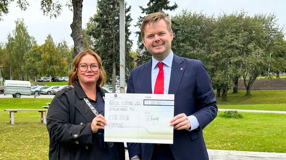 To personer viser fram en stor sjekk på en million kroner.