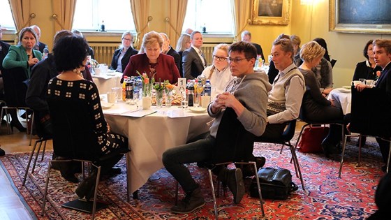 Erna Solberg på sitt bord sammen med andre deltakere.