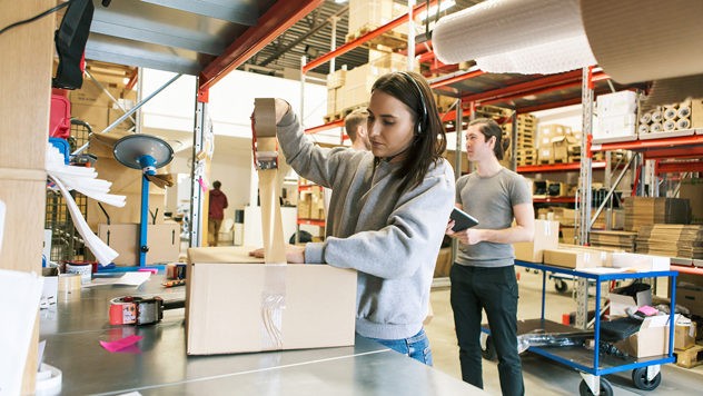 Kvinne pakker inn en pakke på et lager. 