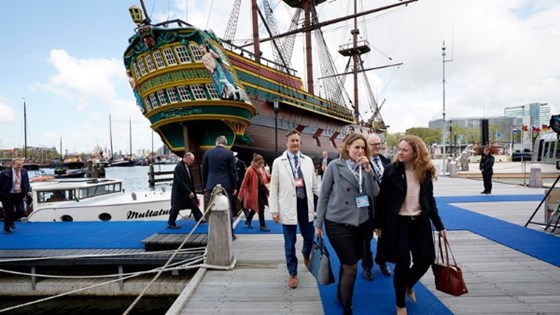 Bilde Anniken Hauglie på blå løper under møte for arbeids- og sosialministre i Amsterdam. Gammel seilskute i bakgrunnen.