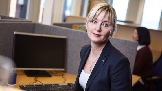 Trude Webb sittende ved kontorpult i kontorlandskap.