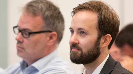 Eivind Thomassen (til venstre) og Lars Fredrik Øksendal sitter og lytter på innlegg i konferansesal.
