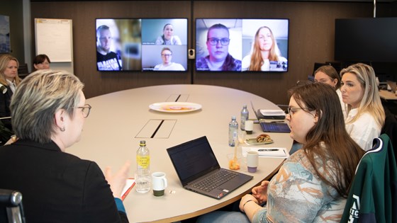 Arbeids- og inkluderingsminster Marte Mjøs Persen sitter rundt et kontorbord med tre representanter for unge brukerorganisasjoner. Fem deltagere er med digitalt på skjermen foran dem.