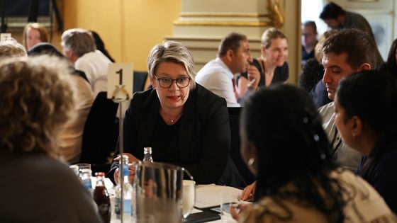 Arbeids- og inkluderingsminister Marte Mjøs Persen sitter rundt et bord med fem mennesker og prater.