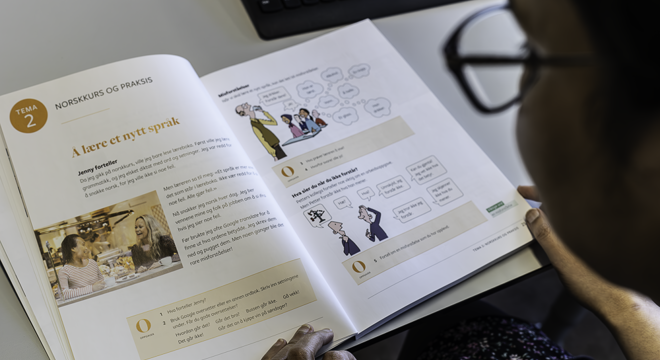 En dame som leser i en norskbok for å tileigne seg norskkunnskaper