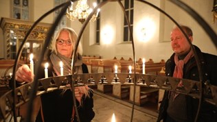 Kvinne som tenner et lys i kirken.