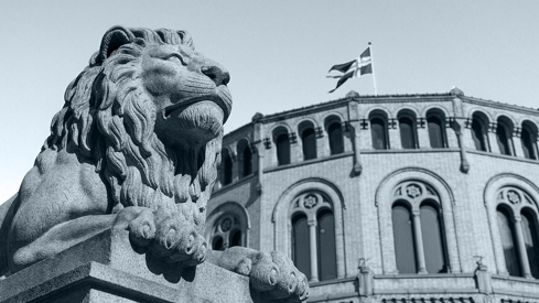 Løvestatue med stortingsbygningen i bakgrunnen