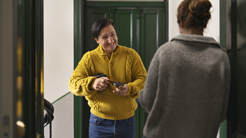 To personer snakker sammen i døråpning i en trappeoppgang.
