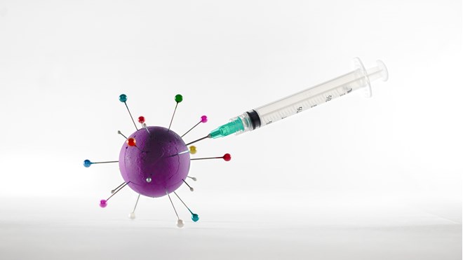 Sprøyte stukket inn i modell av koronavirus