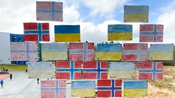 Tegninger av norske og ukrainske flagg som er hengt opp på et vindu mot en skolegård