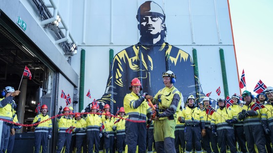 Statråden og en annen mann klipper snor, mens mange arbeidere står i bakgrunnen med norske flagg