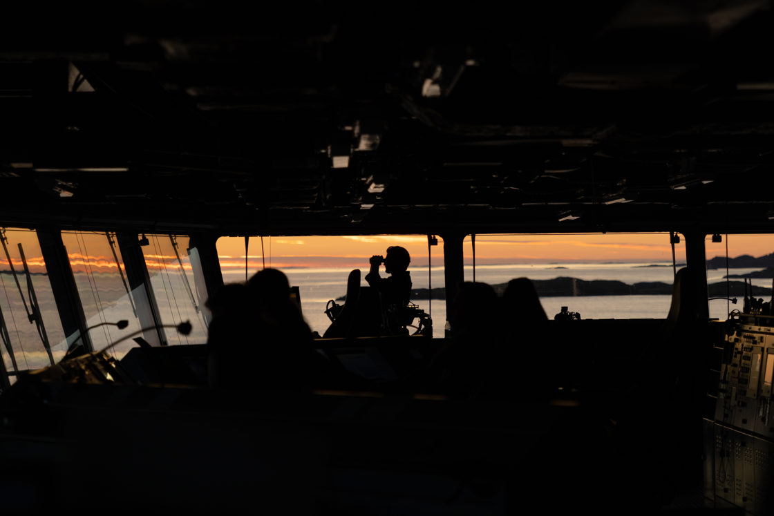 Vernepliktig takkel-gast fra KNM Maud står utkikk på bro. Å stå utkikk på et marinefartøy betyr å observere omgivelsene og rapportere alt som kan påvirke skipets sikkerhet, som andre fartøy, hindringer eller nødsituasjoner.